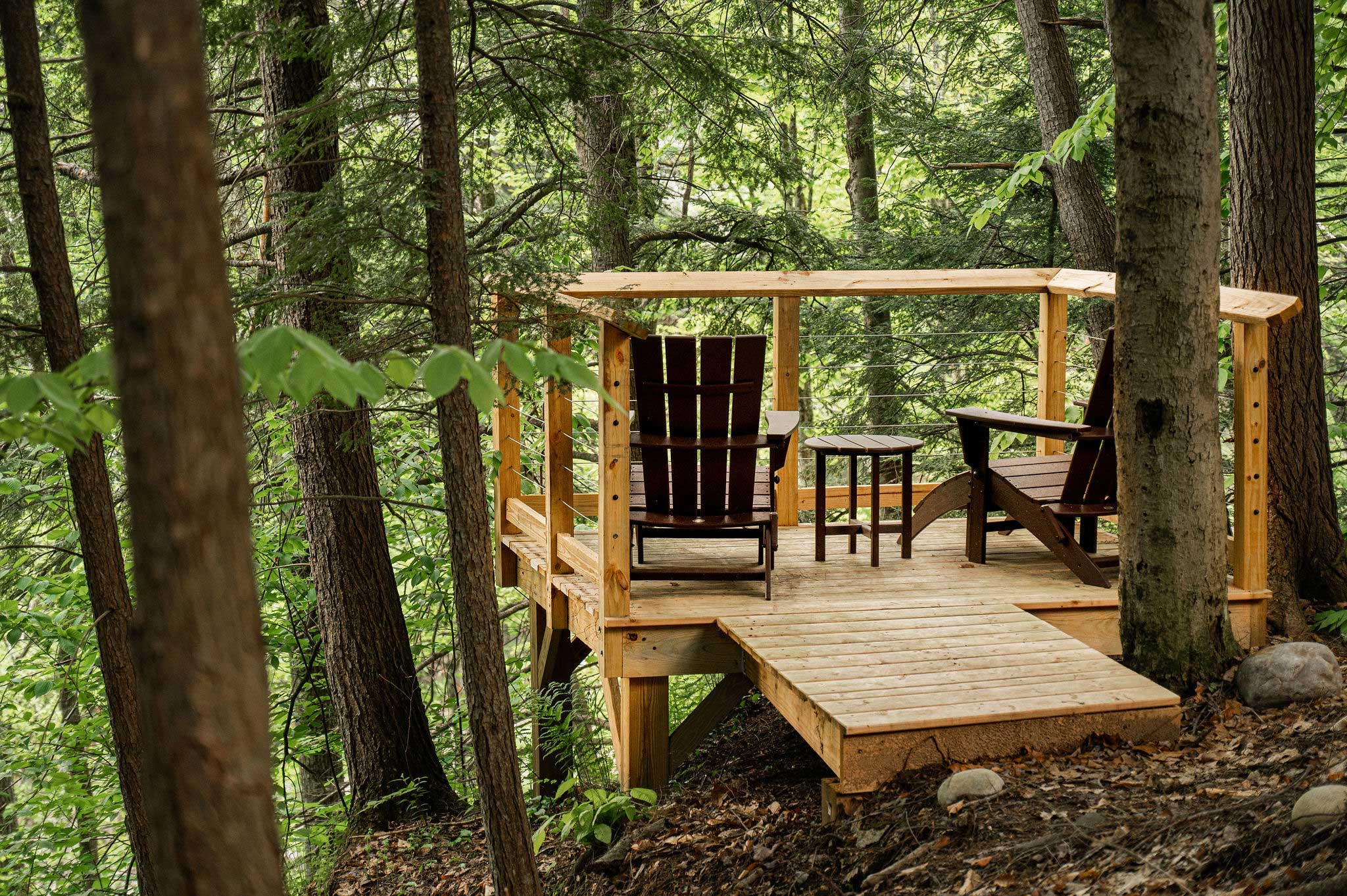 The Overlook wooden platform, with a railing and two large Adirondack chairs.