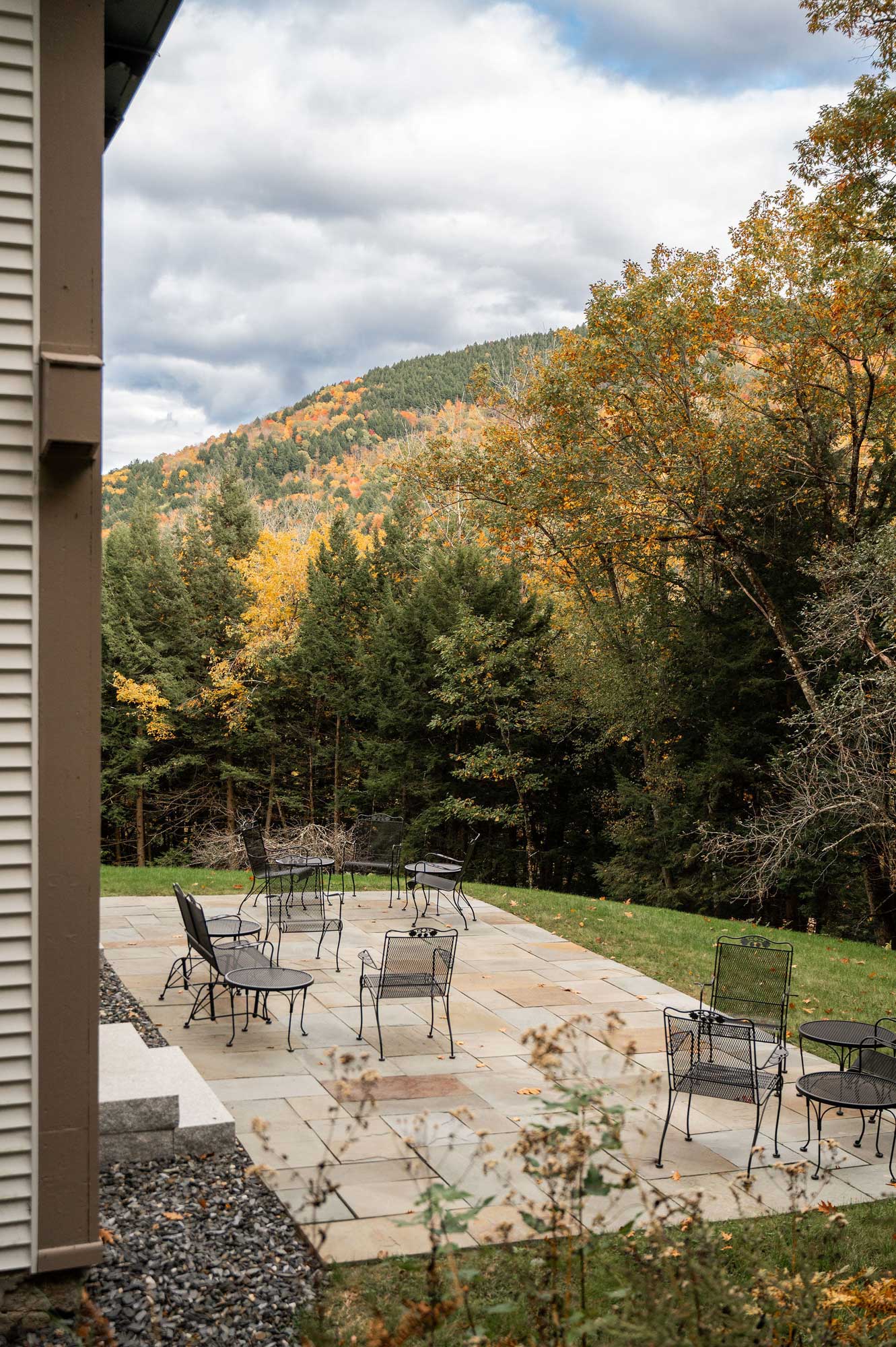 the bluestone terrace with wrought iron seating and a hill with autumn foliage in the background