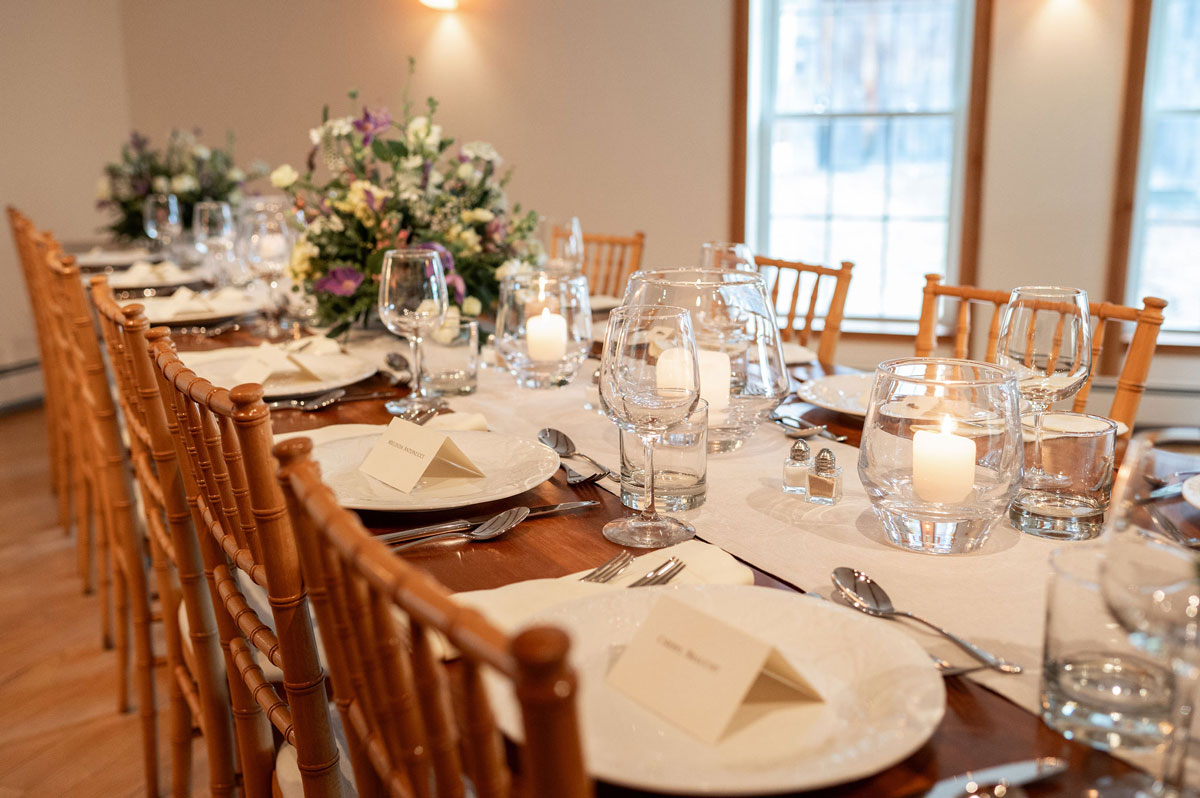 The Cobble House Music Room A table in the Music Room set with a large centerpiece of flowers, and fine dishes, cutlery, and glassware.