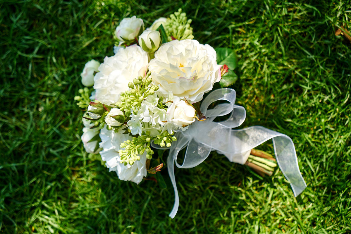 wedding bouquet a bride's bouquet of white flowers tied with a white ribbon lying on a green lawn