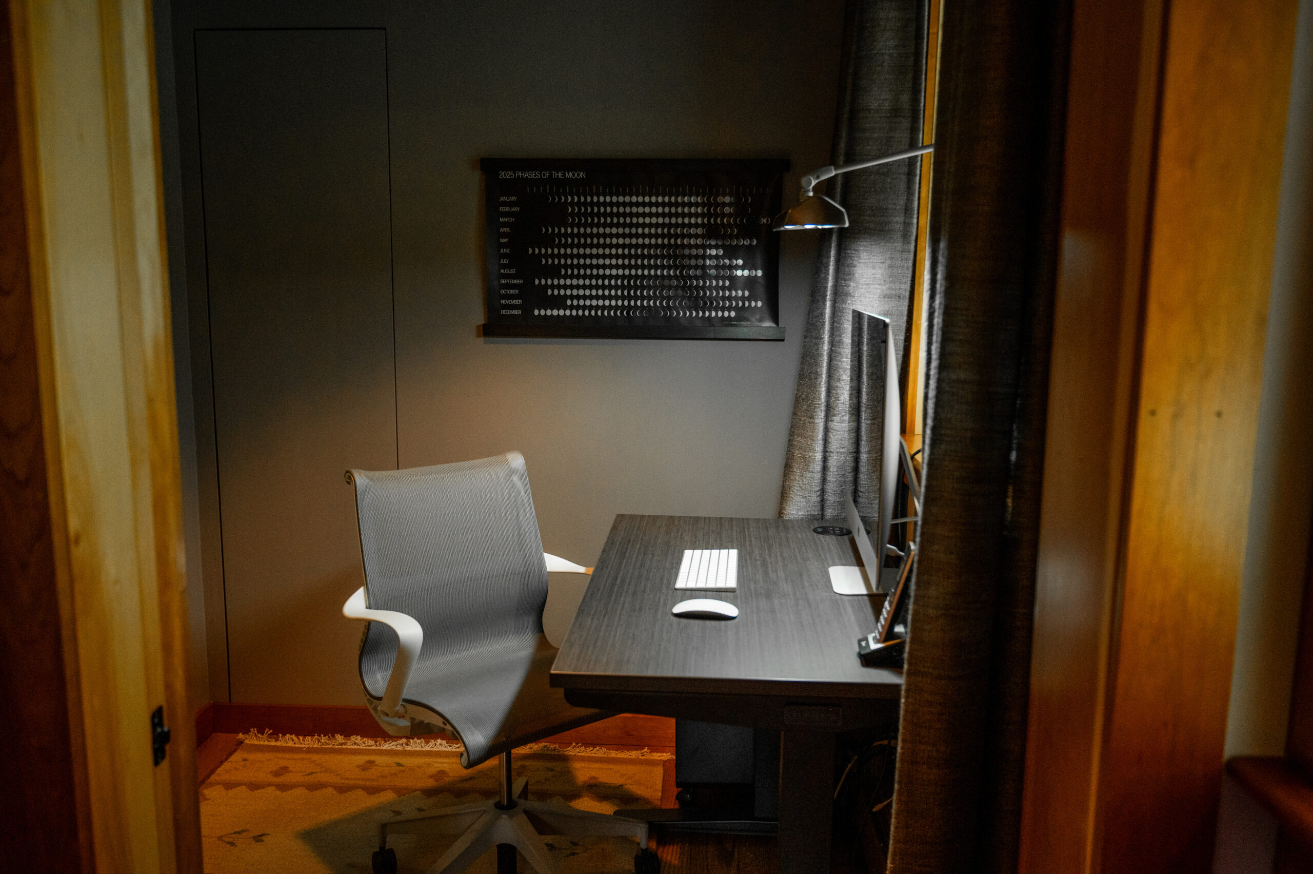 A view of the office showing a desk chair and desk with computer, lit sunlight coming through a window