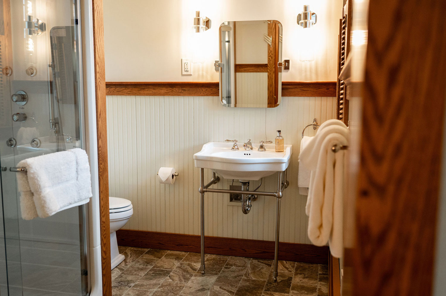 The bathroom sink and mirror with a corner of the shower.