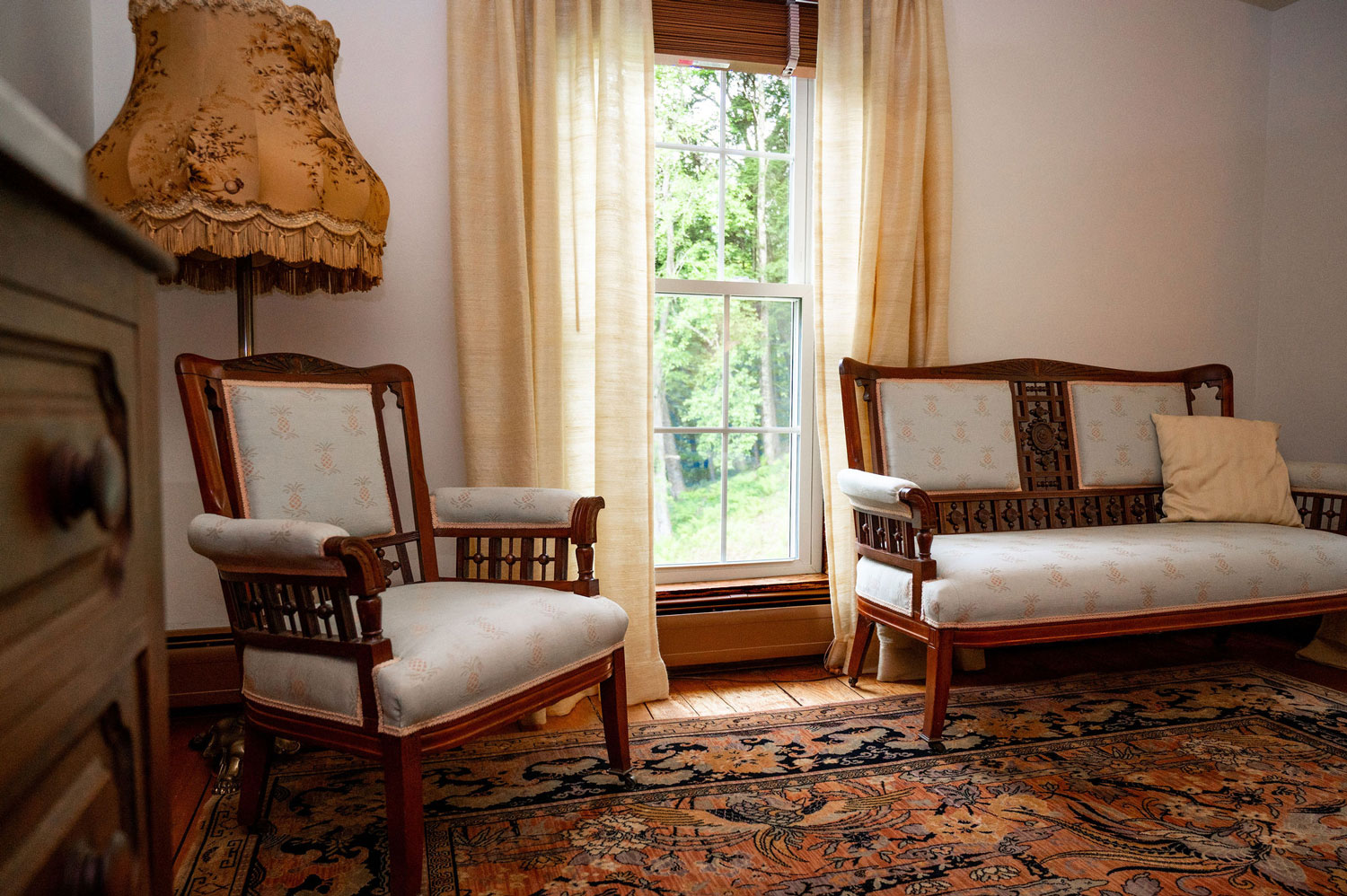 an armchair and a loveseat flanking a window in the Victorian bedroom