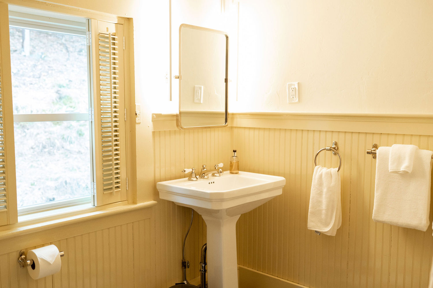 The Victorian bathroom with a pedestal sink and yellow wainscoting
