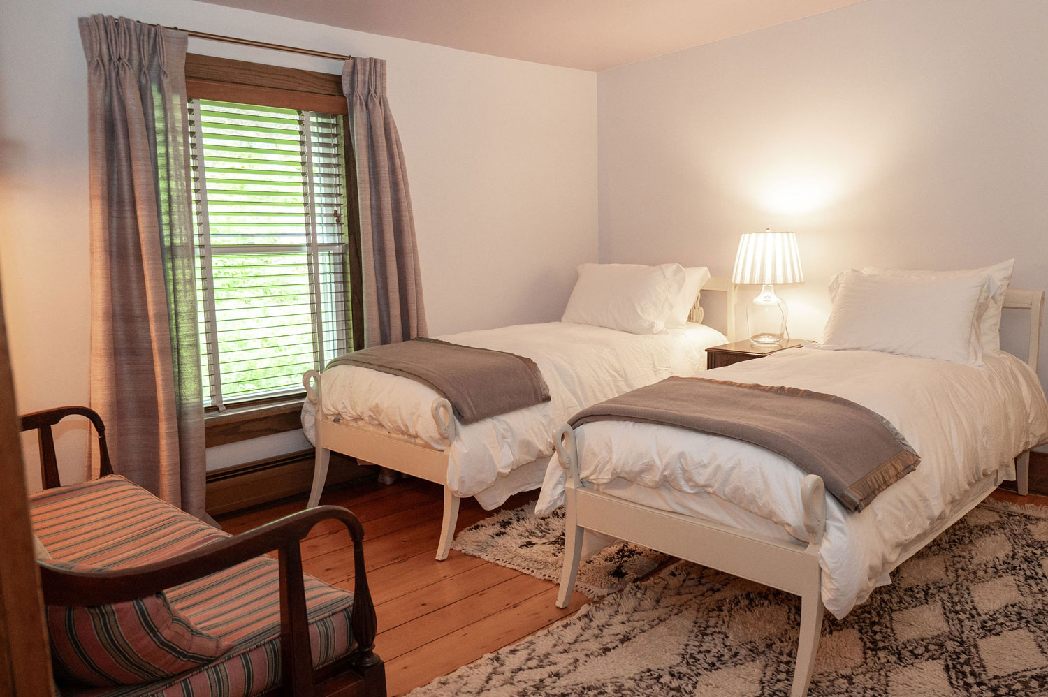 The Woodland Suite beds reflected in a round wood-framed dresser mirror.