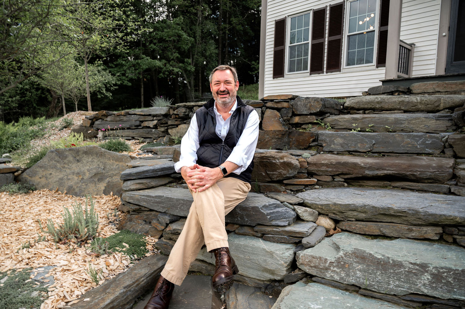 The Cobble House owner Kevin Travis Kevin Travis. owner of the The Cobble House, sitting on stone steps leading up to the front door and smiling.