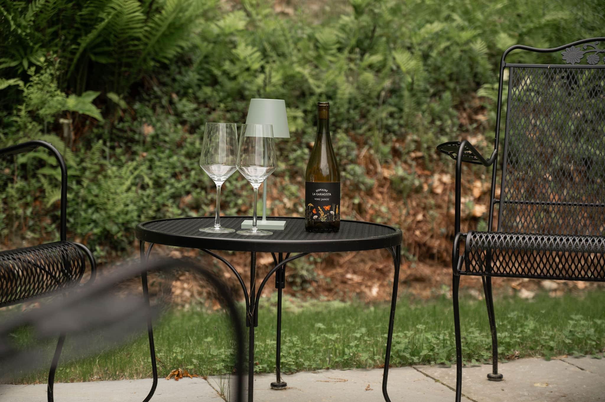 The Cobble House Terrace A wrought iron table and two chairs, with wine glasses and a bottle of wine on the table.